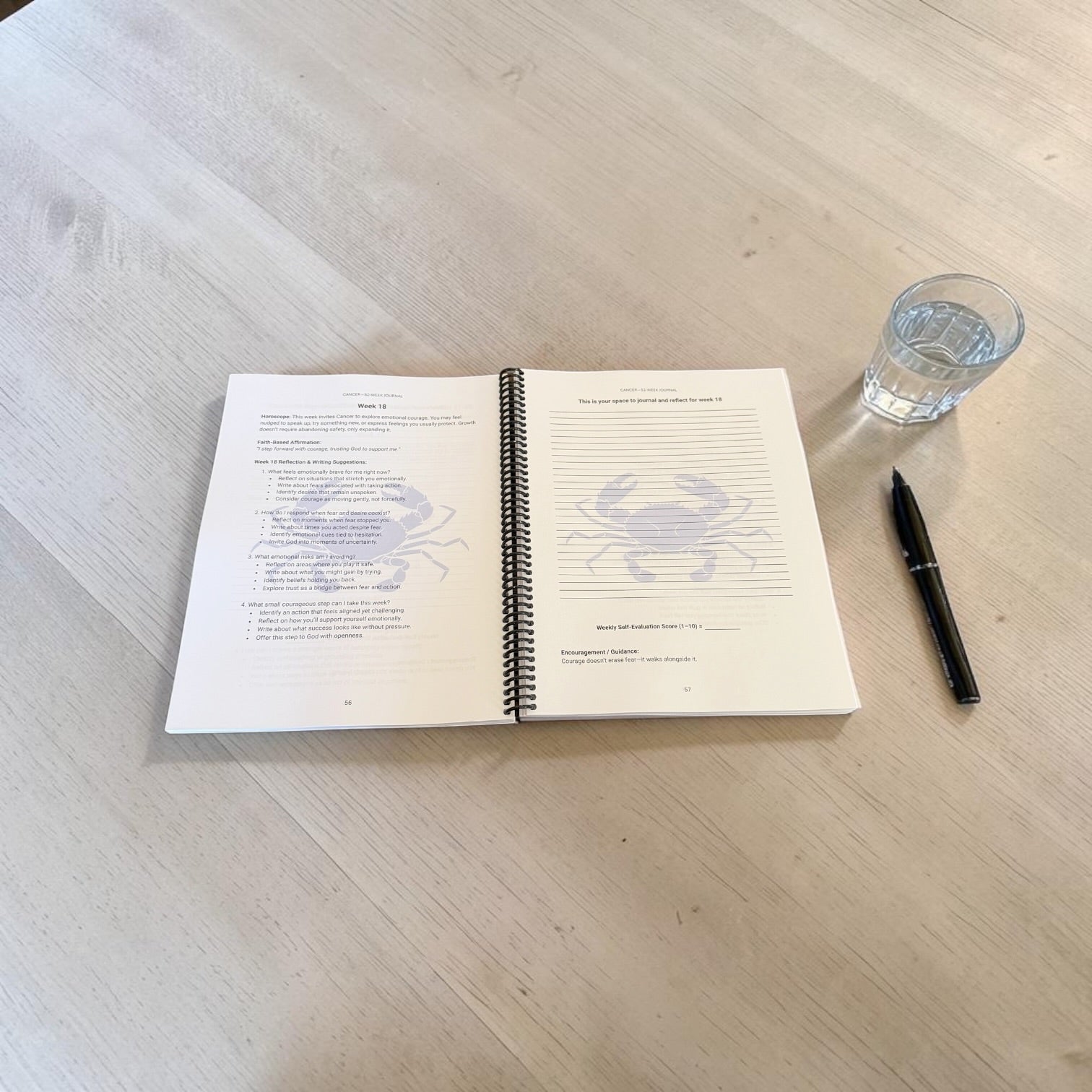 Cancer 52-Week Zodiac journal interior lay-flat image on a wooden table with a pen and glass of water