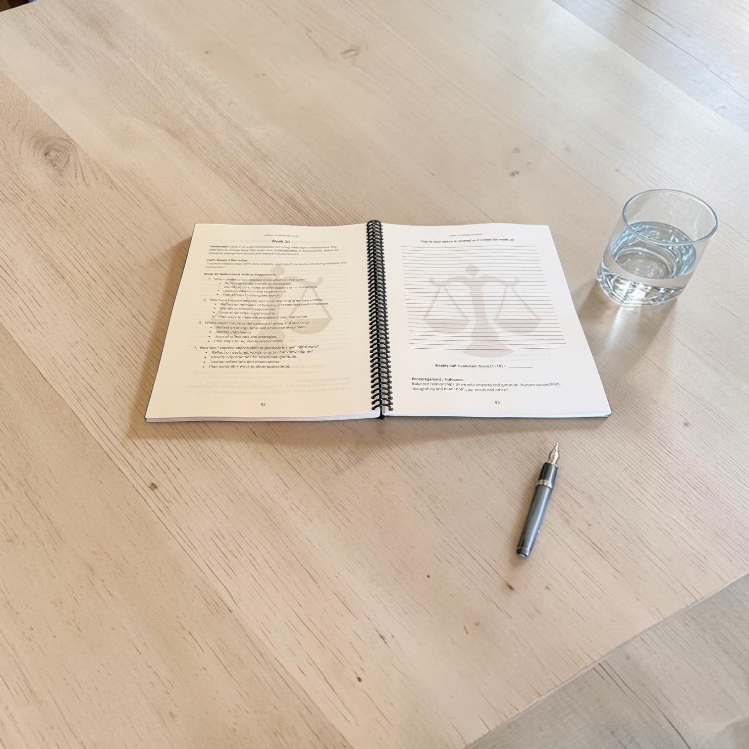 Libra 52-Week Zodiac Journal interior lay-flat image with glass of water and a black pen on a table